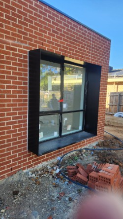 Wide aluminium window shroud over sliding door on brick home — northern Melbourne